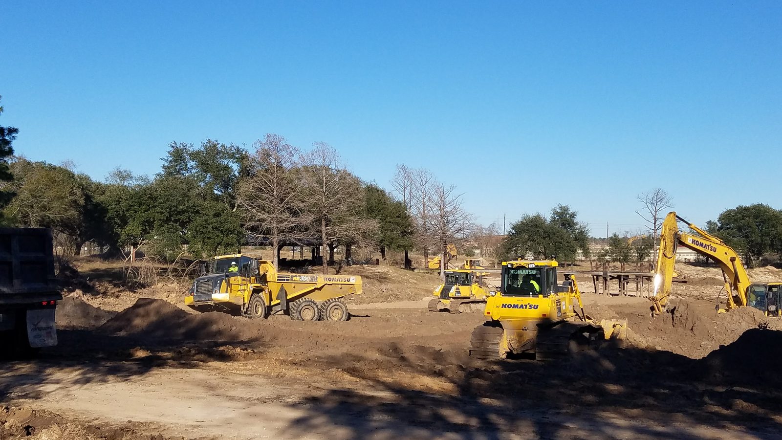 GMS land clearing operation with articulated dump truck, bulldozer, and excavator at Greater Houston tract